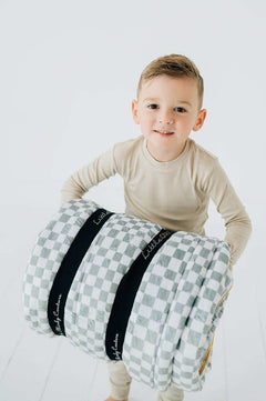 Child carrying a rolled Sage Check Sleeping Bag from Little Couture by Minky Couture.