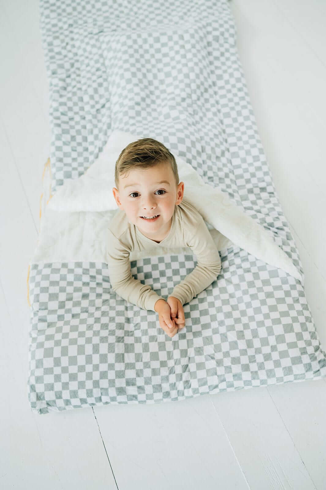 Child inside Sleeping Bag Sage Check, showcasing cozy Minky Couture design with stylish check pattern.
