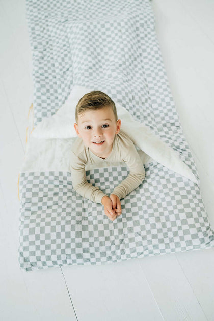 Child inside Sleeping Bag Sage Check, showcasing cozy Minky Couture design with stylish check pattern.