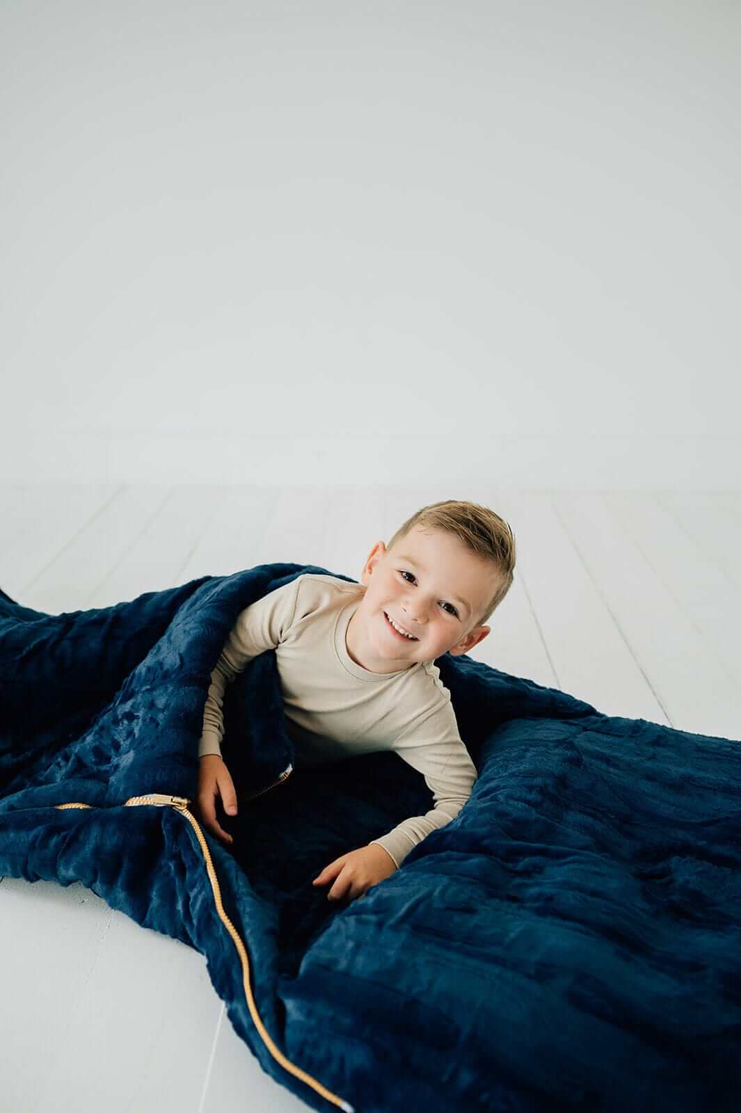 Child wrapped in the Sleeping Bag in Navy color, showcasing its cozy Minky Couture design and plush texture.