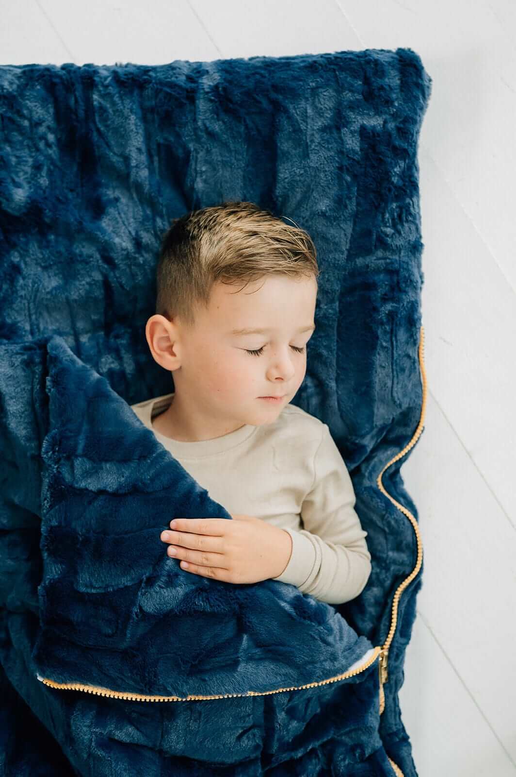 Navy Sleeping Bag with a child relaxing comfortably inside, showcasing the plush Minky fabric and cozy design.