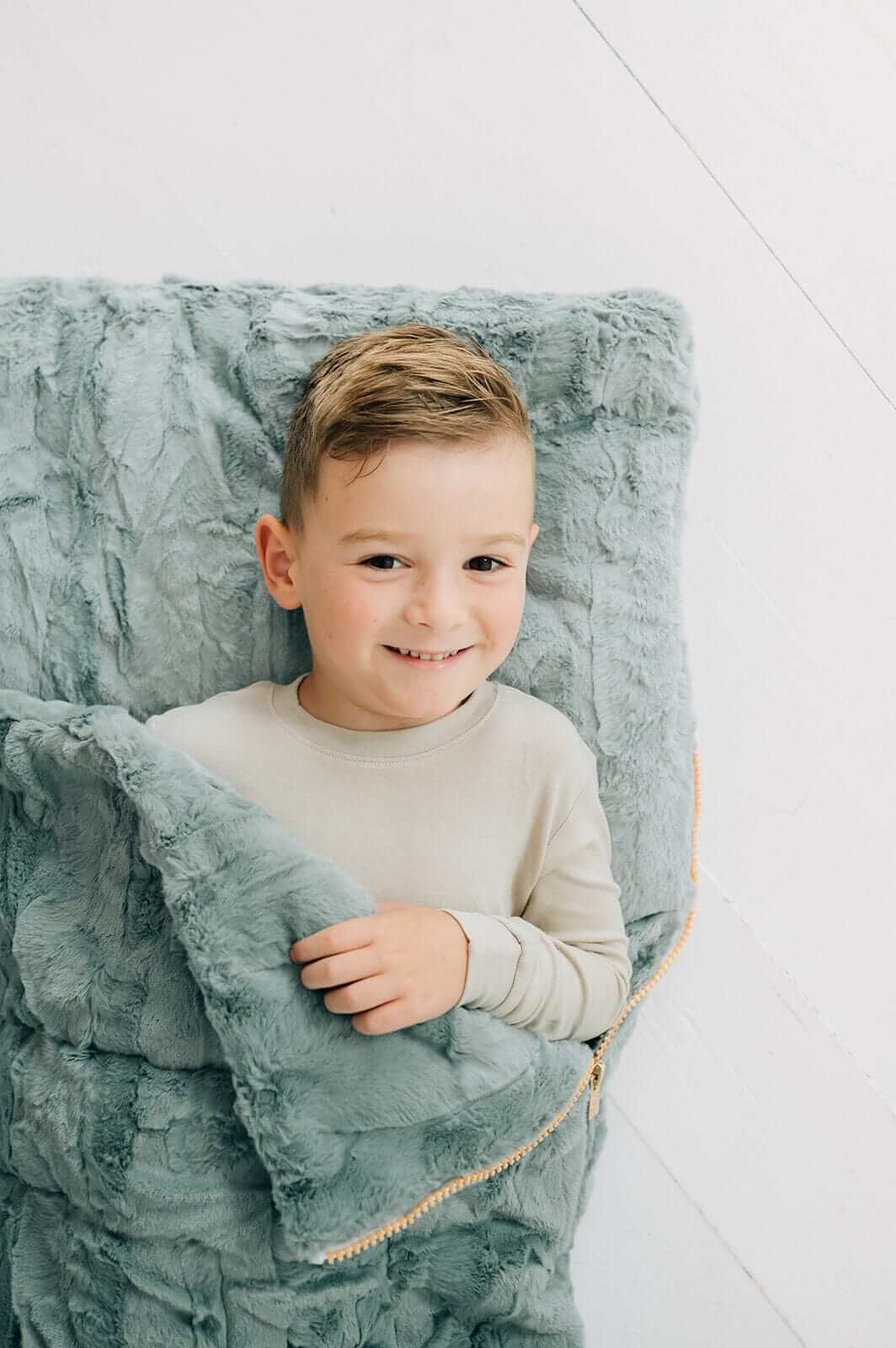 Plush Mist Sleeping Bag with a happy boy snuggling inside the cozy plush material.