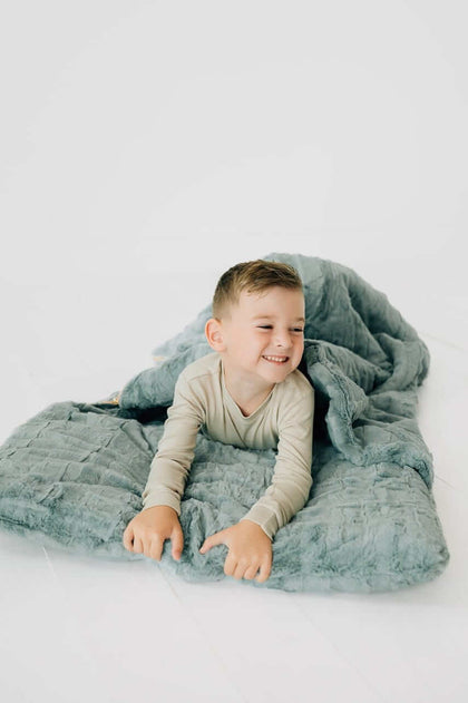 Child enjoying the Plush Mist Sleeping Bag from Little Couture with a cheerful smile.