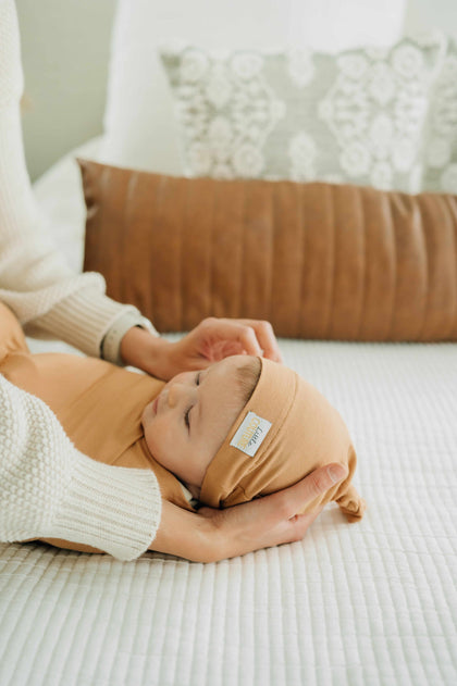 Swaddle and Hat Baked Apple Pie on a cozy bed, showcasing a baby wrapped snugly in a bamboo swaddle and matching hat.