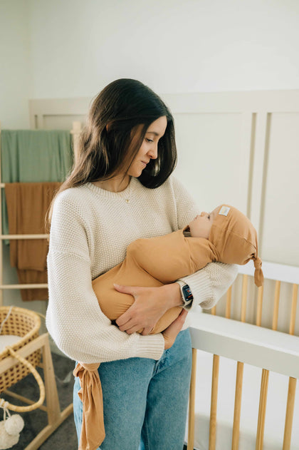 Cozy bamboo Swaddle and Hat Baked Apple Pie set for baby comfort, held by a smiling parent.