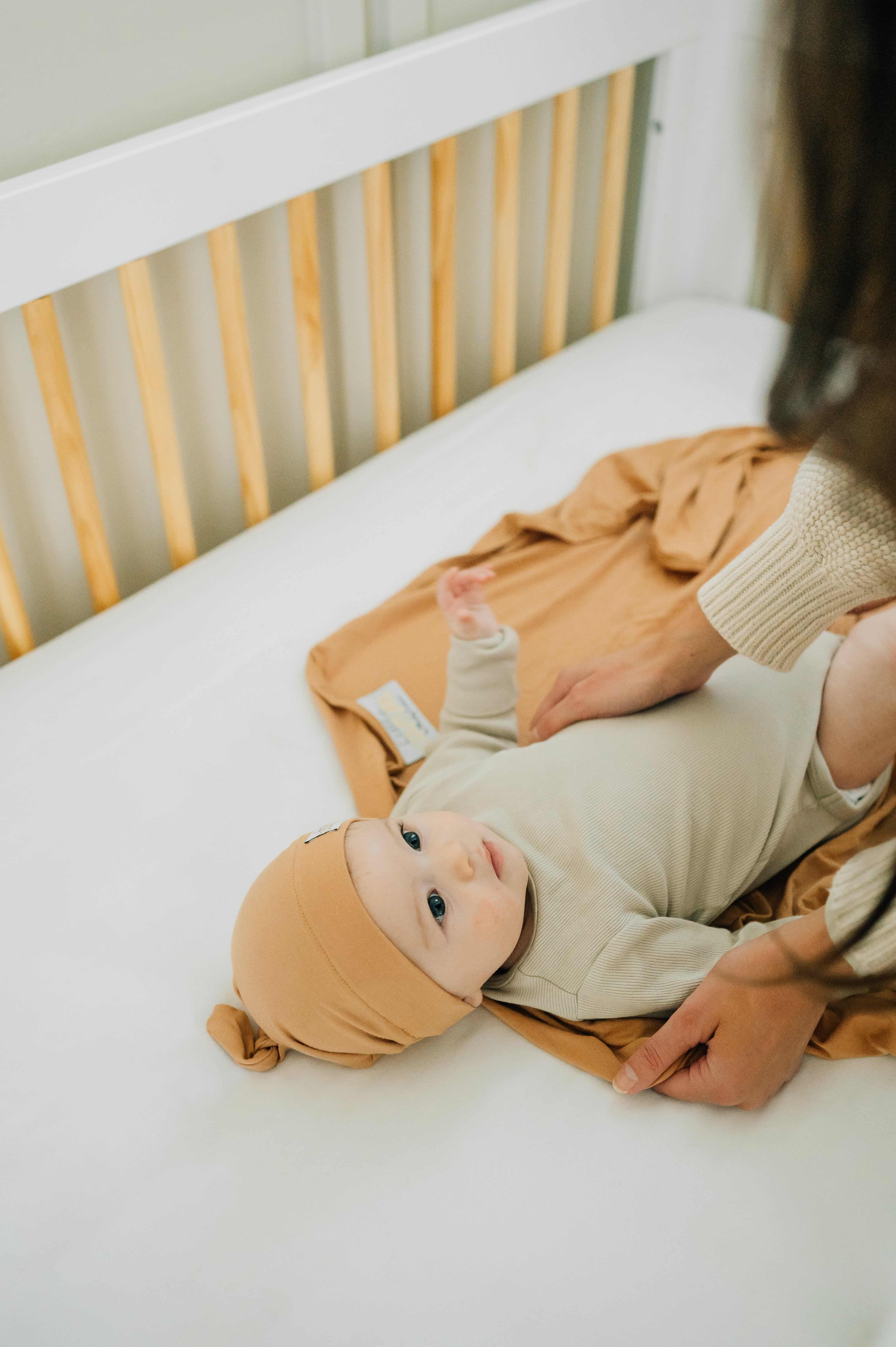 Swaddle and Hat Baked Apple Pie, baby bundled in soft bamboo swaddle and matching hat in a crib.