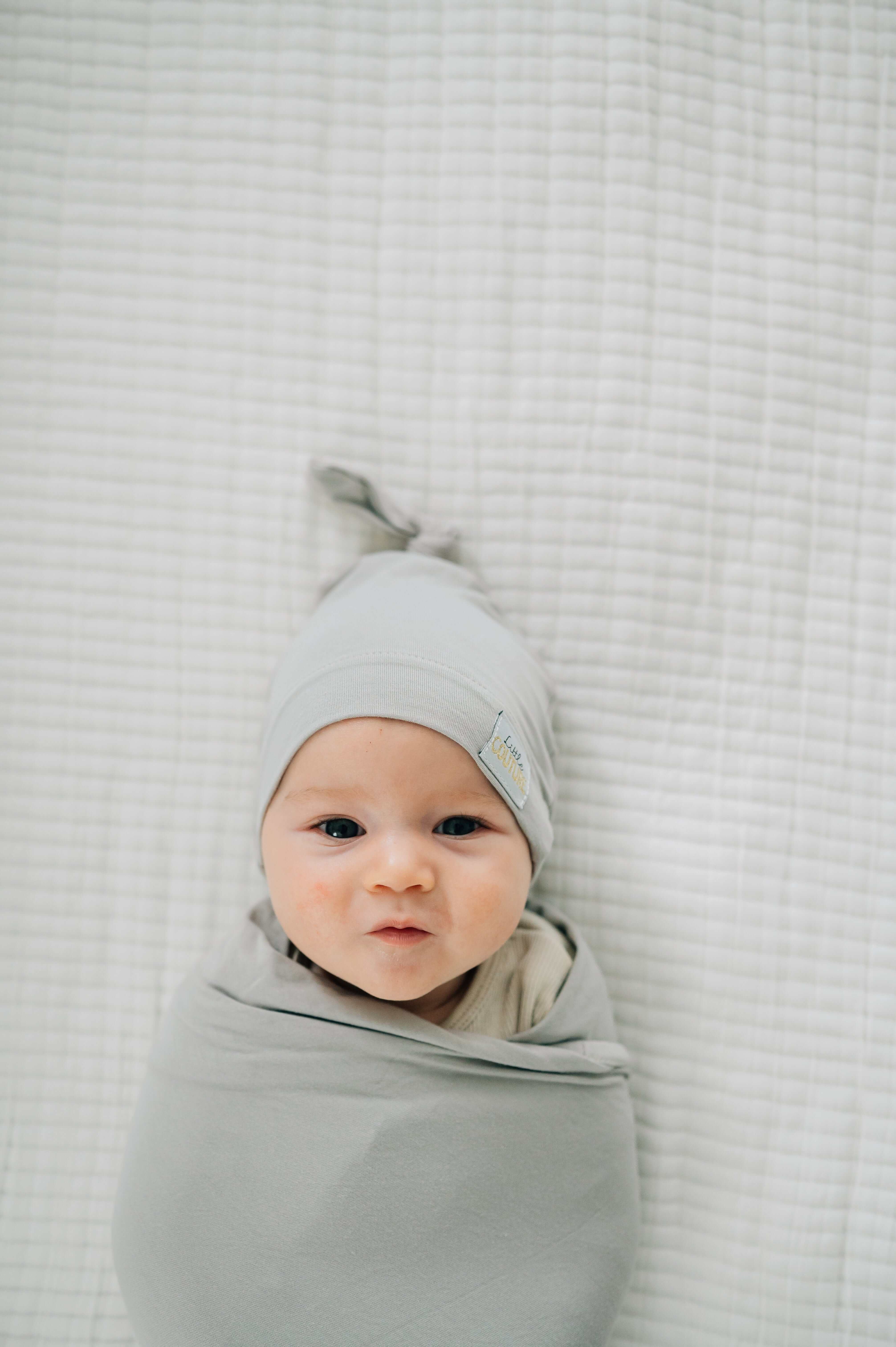Baby wrapped in a soft bamboo Swaddle and Hat Tranquil Dove, looking cozy and adorable.