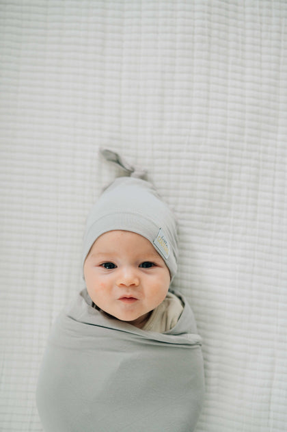 Baby wrapped in a soft bamboo Swaddle and Hat Tranquil Dove, looking cozy and adorable.