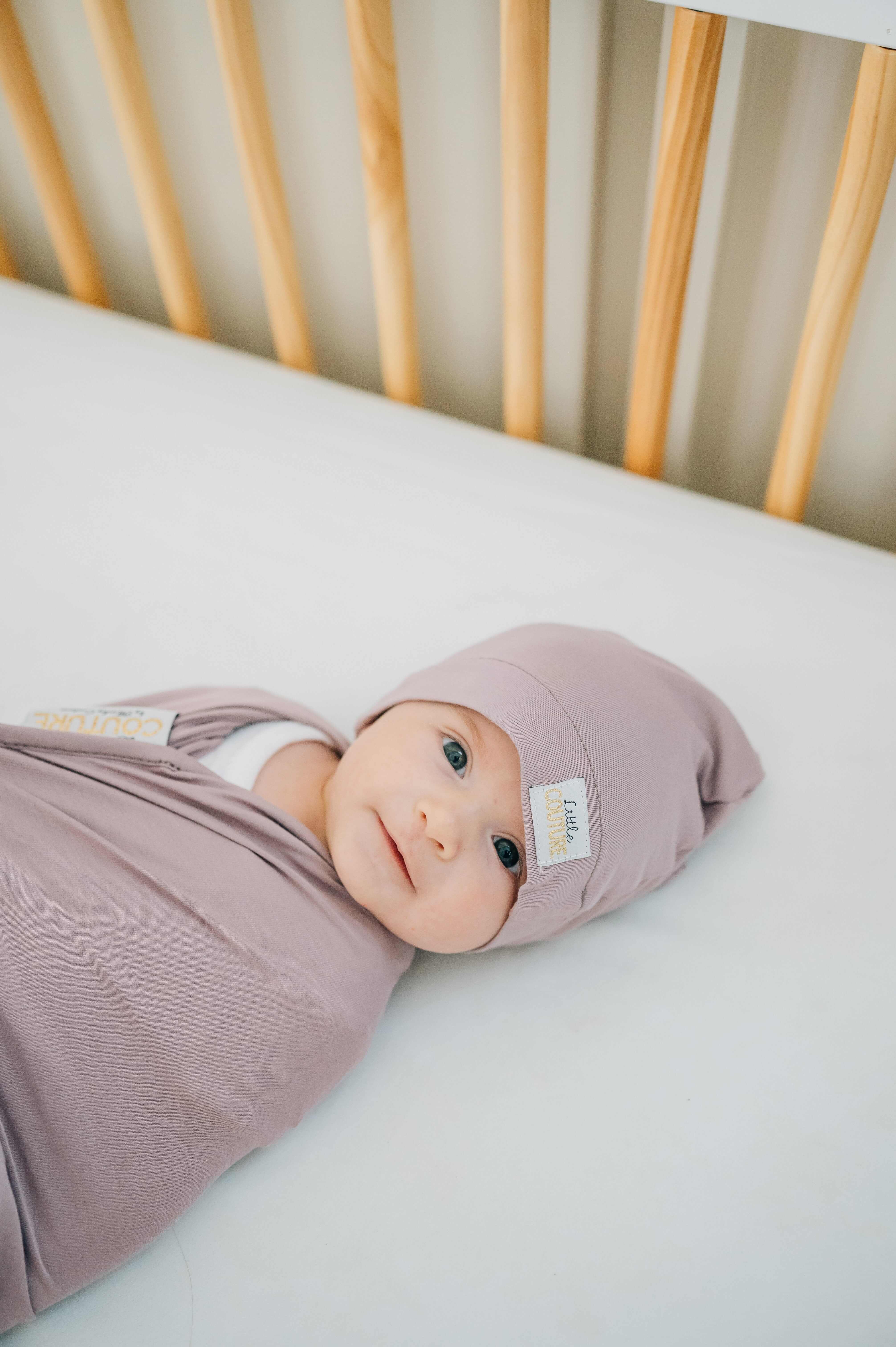 Swaddle and Hat Blueberry Cheesecake combo with a cozy baby in a crib, wrapped in soft bamboo fabric.
