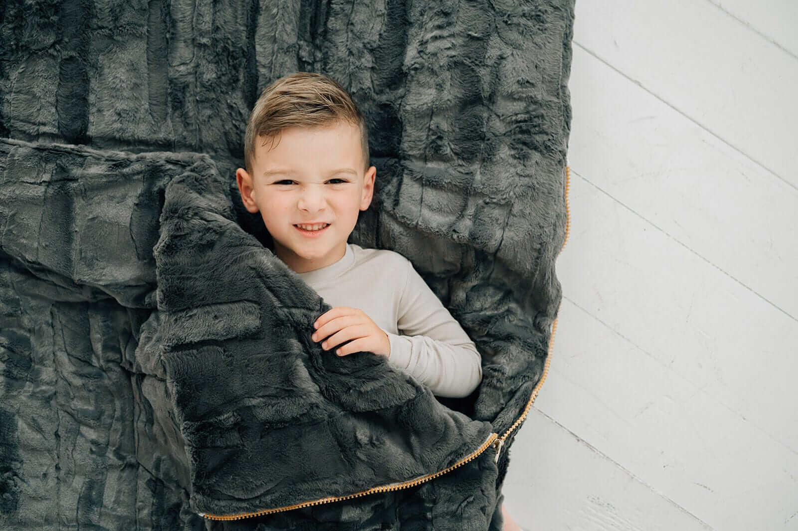 Child nestled in a Sleeping Bag in Charcoal, showcasing the plush texture and cozy design of Minky Couture.