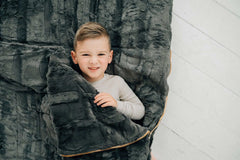 Child nestled in a Sleeping Bag in Charcoal, showcasing the plush texture and cozy design of Minky Couture.