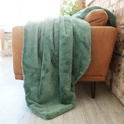 Lush Midnight Mist Blanket draped over a chair, showcasing its luxurious misty green plush fabric and cozy ambiance.