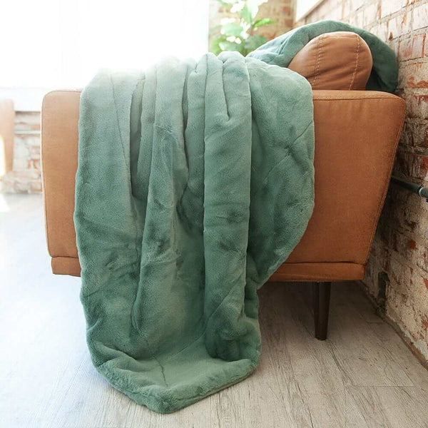 Lush Midnight Mist Blanket draped over a chair, showcasing its luxurious misty green plush fabric and cozy ambiance.