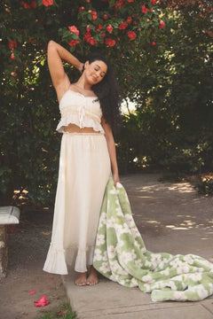 Model showcasing the Lush Mist Floral Blanket outdoors while wearing a light summer outfit.