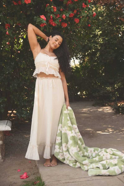 Model showcasing the Lush Mist Floral Blanket outdoors while wearing a light summer outfit.