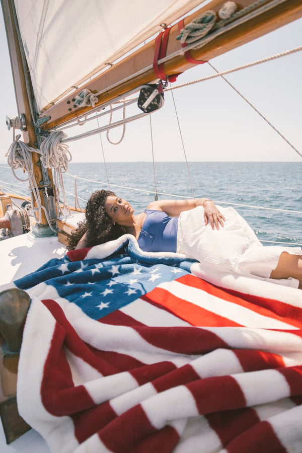 Woman lying on a sailboat with an American flag blanket