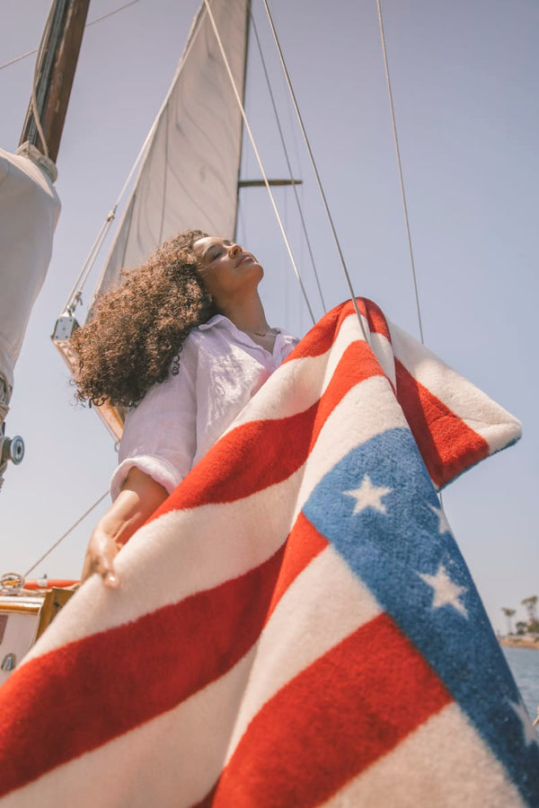 Person holding an American flag blanket on a boat with a clear sky background