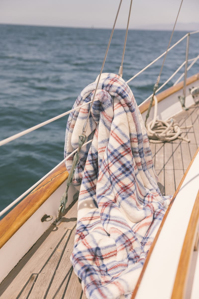 Plaid blanket draped over a boat's railing with ocean in the background