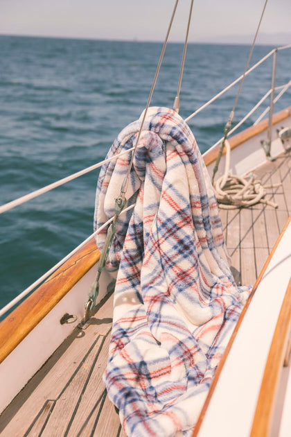 Plaid blanket draped over a boat's railing with ocean in the background