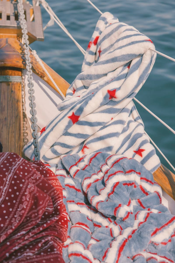 Striped blanket with red stars draped over a railing with water in the background