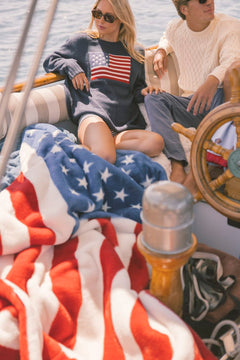 Two people on a boat with an American flag-themed blanket.