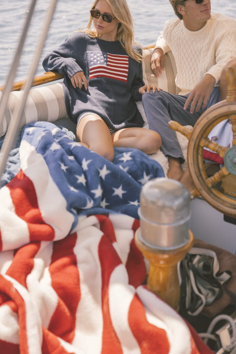 Two people on a boat with an American flag-themed blanket.