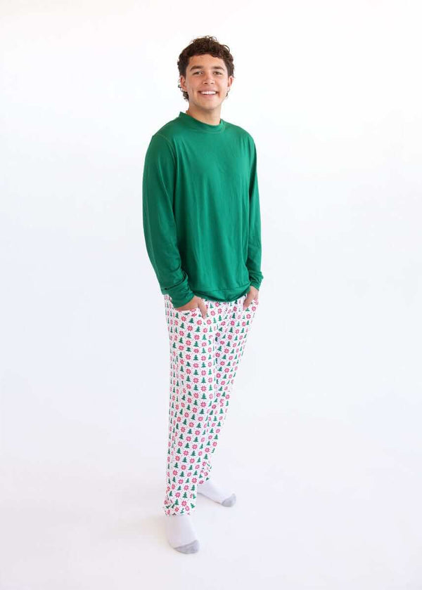 Man wearing a green Montage Men's Pajama long-sleeve top and white Christmas tree pajama pants, standing against a white background.