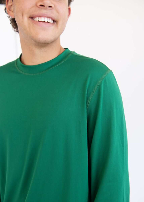 Close-up of a man wearing a green  long-sleeve Montage Men's Pajama shirt, smiling, against a white background.