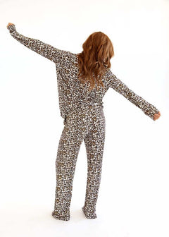 Back view of a woman wearing a leopard print Minky Couture pajama set with arms extended on a white background.