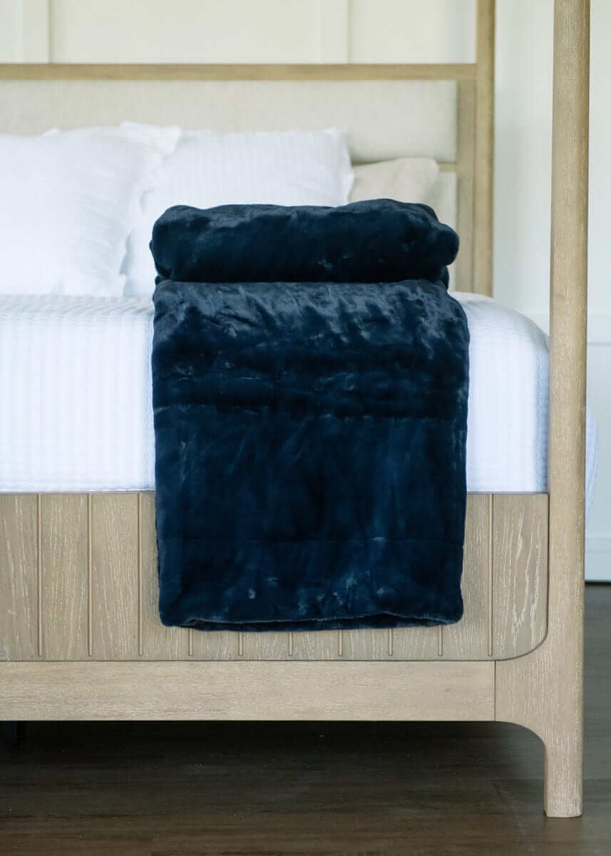 Lush Night Sky Blanket draped over a bed, showcasing its plush dark blue fabric and cozy design.