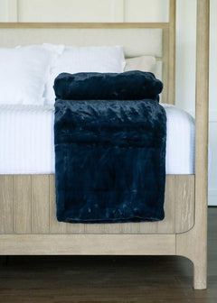 Lush Night Sky Blanket draped over a bed, showcasing its plush dark blue fabric and cozy design.