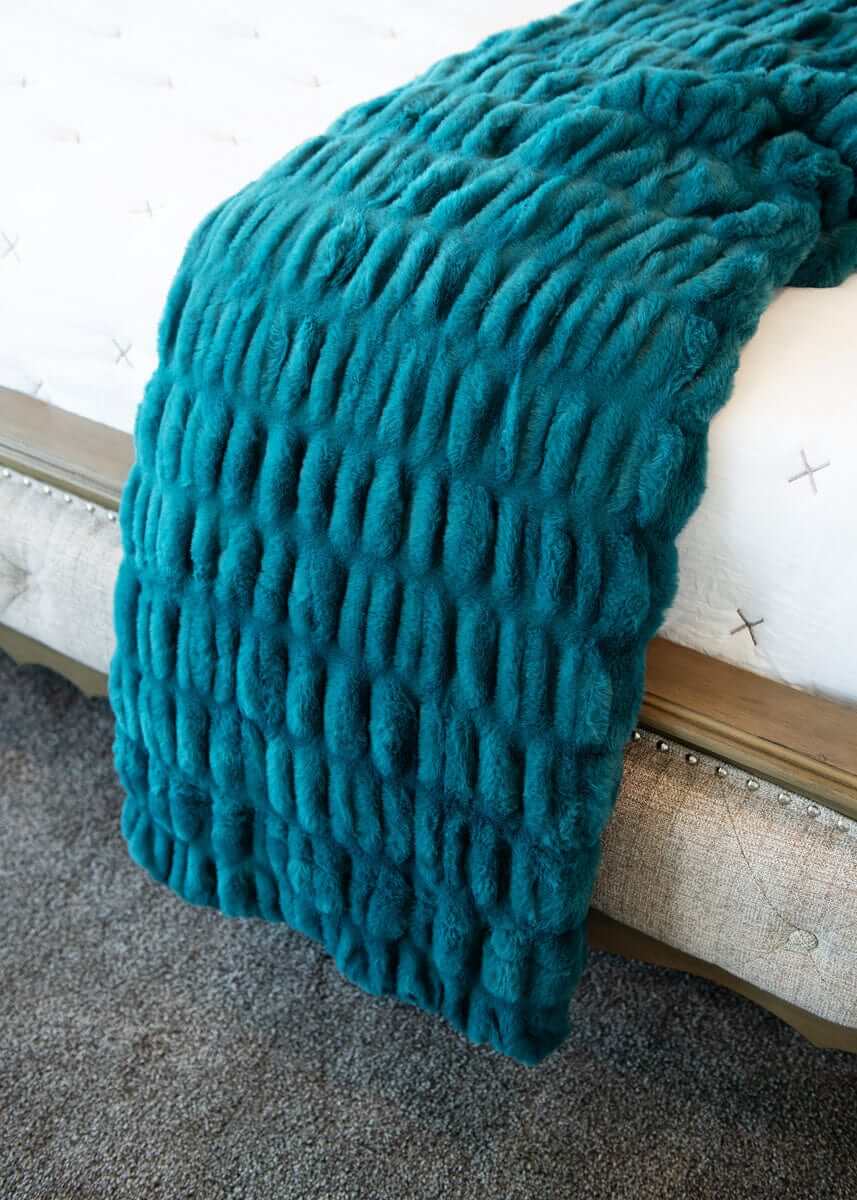 Hugs Deep Lake Blanket draped over a bed, showcasing its plush texture and serene deep blue hue.