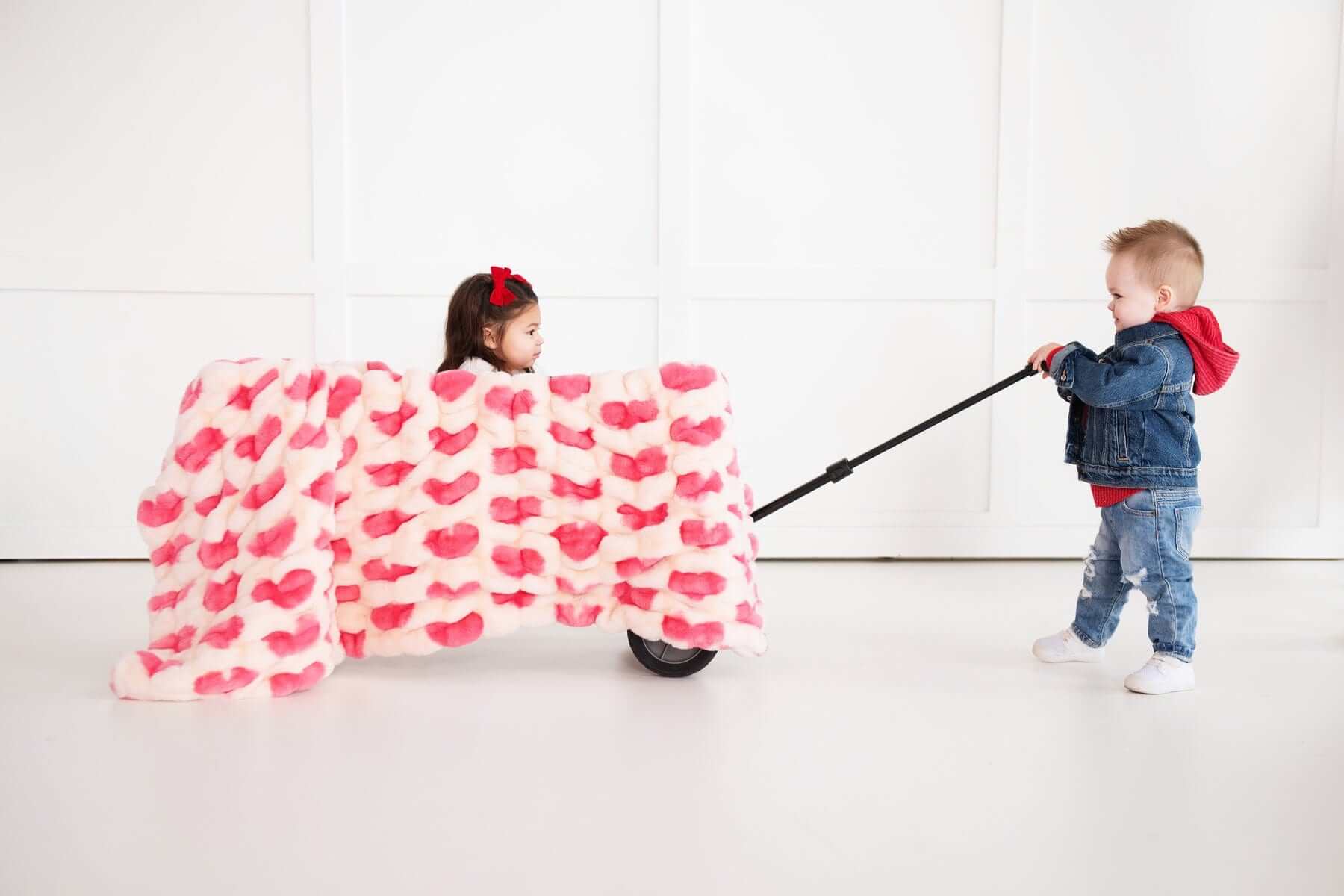 Children playing with the Minky Couture Hugs Heart Pink Blanket, featuring pink hearts, creating a cozy atmosphere.