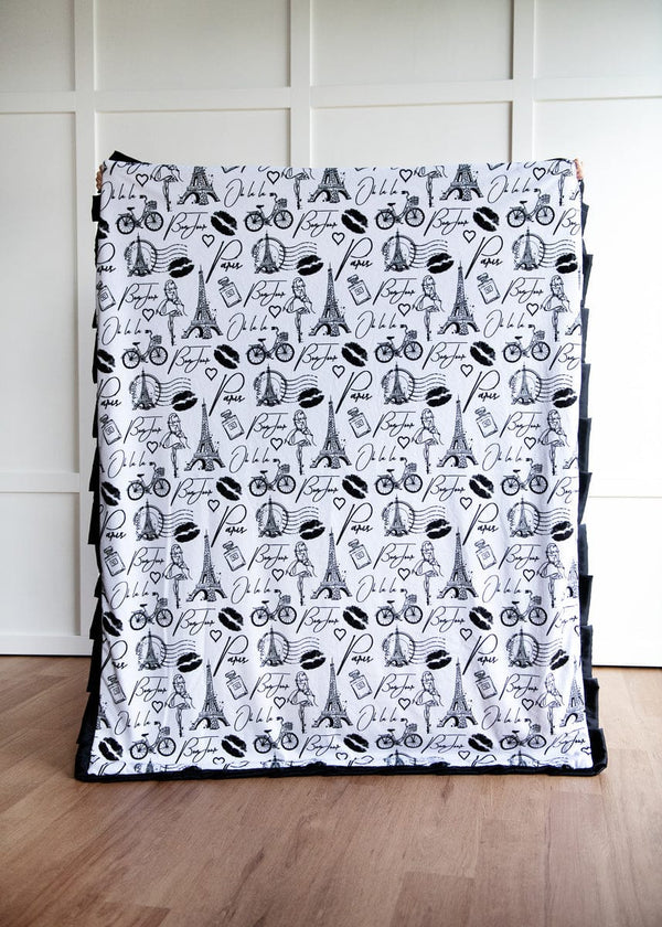 Patterned blanket with black and white design on a wooden floor.