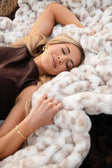 Woman lying on a snow leopard-print Hugs Snow Leopard Minky Couture faux fur blanket.