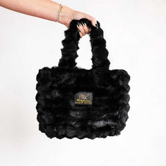 Hand holding a black Minky Couture Annie bag made from soft plush fabric.