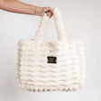 Cream Minky Couture Annie bag with plush texture, shown hanging from a hand against a white background.