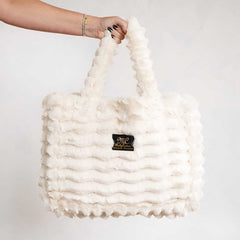 Cream Minky Couture Annie bag with plush texture, shown hanging from a hand against a white background.