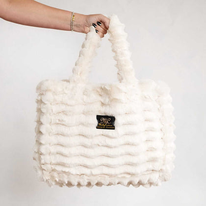 Cream Minky Couture Annie bag with plush texture, shown hanging from a hand against a white background.