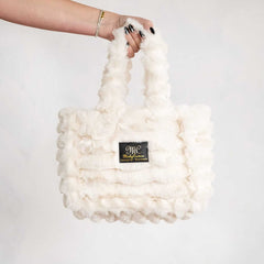 Hand holding a cream Minky Couture Annie bag made from soft plush fabric.