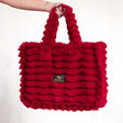 Red Minky Couture Annie bag with plush texture, shown hanging from a hand against a neutral background.