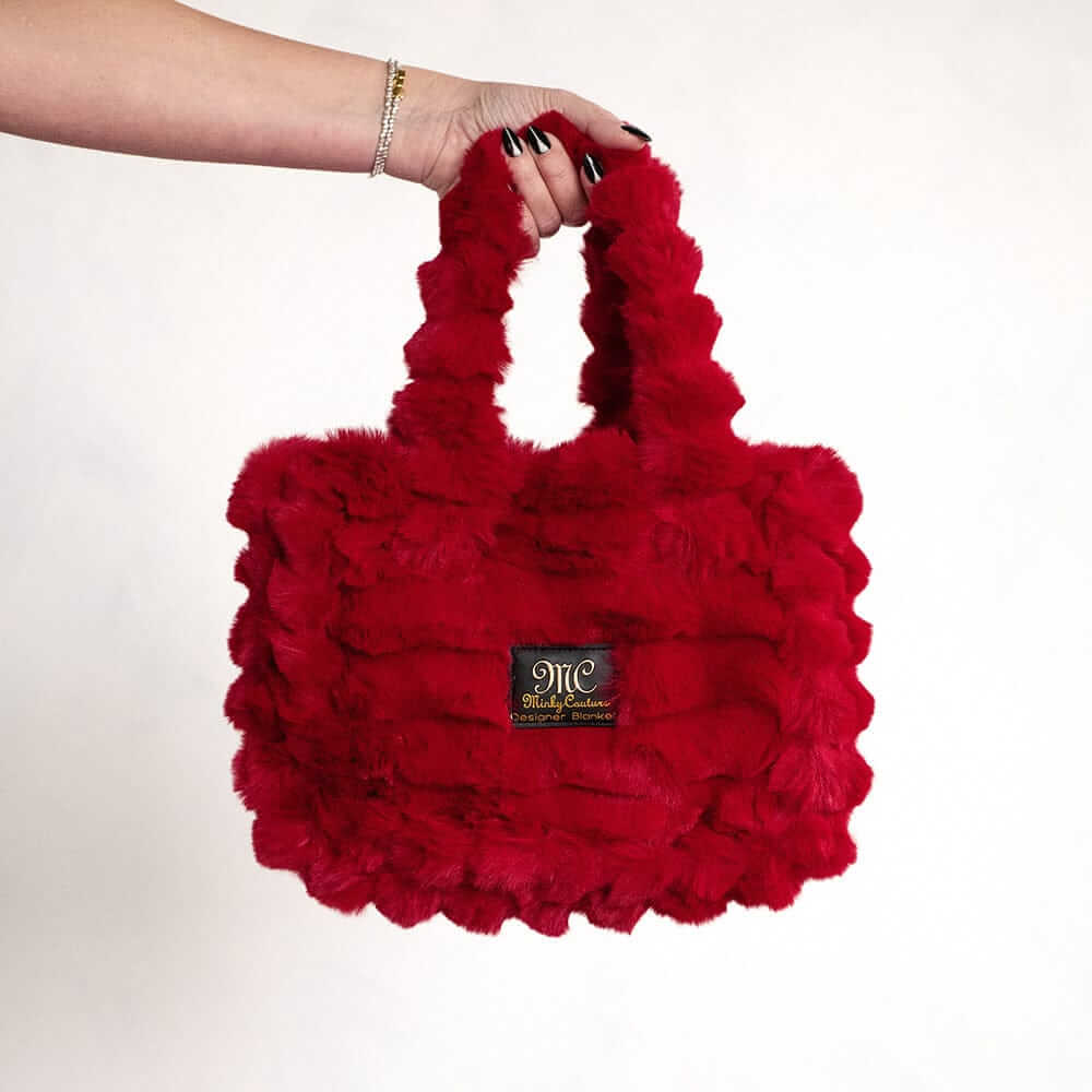 Hand holding a red Minky Couture Annie bag made from soft plush fabric.