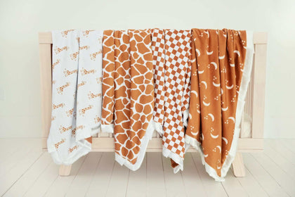 Minky Couture Blankets displayed among other cozy blankets on a wooden rack.
