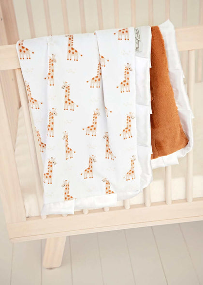 Little Giraffe Blanket draped over a crib, featuring playful giraffe designs and plush backing.