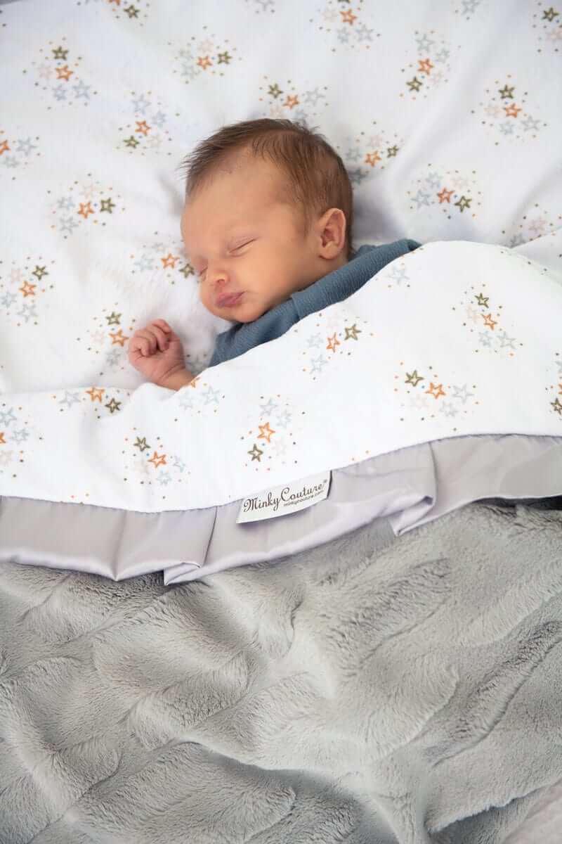 Minky Couture Shining Stars Blanket featuring gold, mist, and silver stars with a baby sleeping peacefully.