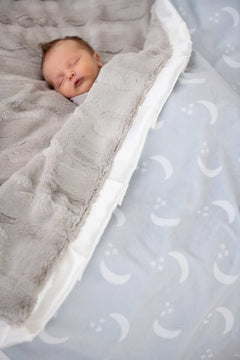 Baby sleeping peacefully under the Minky Couture Shining Moon Silver Blanket featuring soft gray and dreamy moon design.