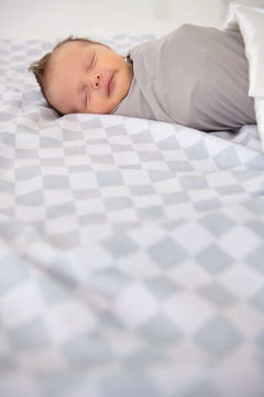 Cozy baby sleeping on a Minky Couture Checkered Silver Blanket featuring a classic gray checkered pattern.