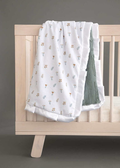 Minky Couture Itsy Bitsy Flower Gold Blanket draped over a crib, showcasing delicate gold and mist flowers on a white background.