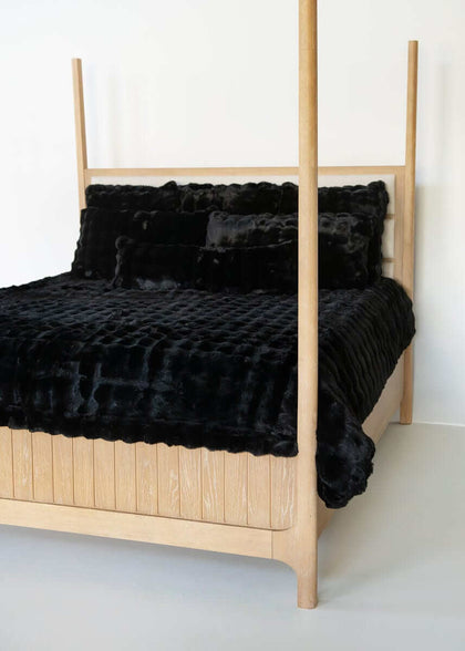 Black Minky Couture duvet and pillows styled on a wooden canopy bed against a white background.