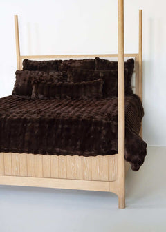 Chocolate Cloud Minky Couture duvet and pillows styled on a wooden canopy bed against a white background.